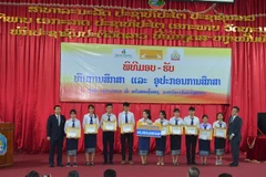 Giám đốc Công ty Bảo hiểm đại chúng Lanexang Đỗ Đăng Khang (ngoài cùng trái) trao học bổng cho sinh viên Đại học quốc gia Lào. (Ảnh: Xuân Tú/TTXVN) 