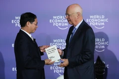 Giáo sư Klaus Schwab, Người sáng lập, Chủ tịch Điều hành Diễn đàn Kinh tế thế giới (bên phải) trao sách tặng Thứ trưởng Thường trực Bộ Ngoại giao Bùi Thanh Sơn. (Ảnh: Lâm Khánh/TTXVN) 