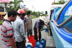 Người dân Rạch Giá phải sử dụng mọi vật dụng hiện có để lấy nước tại các xe bồn cấp nước. (Ảnh: Trường Giang/TTXVN)