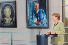 Thủ tướng Đức Angela Merkel phát biểu trong một hội nghị ở Phủ Thủ tướng tại Berlin, bên cạnh lần lượt là ảnh chân dung cựu Thủ tướng Helmut Kohl và cựu Thủ tướng Gerhard Schröder (trái). (Ảnh: Mạnh Hùng/Vietnam+)