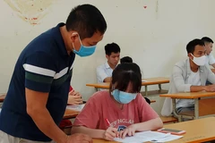 Thí sinh và giám thị cùng đeo khẩu trang vào phòng thi trong kỳ thi Tốt nghiêp Trung học phổ thông 2020. (Ảnh: Phạm Mai/Vietnam+)