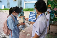 Thí sinh rửa tay sát khuẩn trước khi vào điểm thi thi. (Ảnh: PV/Vietnam+)