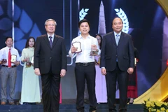 Thủ tướng Nguyễn Xuân Phúc và đồng chí Trần Quốc Vương, Ủy viên Bộ Chính trị, Thường trực Ban Bí thư trao giải A cho tác giả Hùng Võ báo điện tử Vietnamplus, TTXVN. (Ảnh: Doãn Tấn/TTXVN)