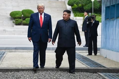 Tổng thống Mỹ Donald Trump (trái) và nhà lãnh đạo Triều Tiên Kim Jong-un bước chân qua đường ranh giới phân chia hai miền Triều Tiên tại DMZ, sang phần lãnh thổ của Triều Tiên chiều 30/6/2019. (Nguồn: AFP/TTXVN)