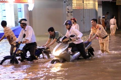 Lực lượng Công an giúp người điều khiển phương tiện giao thông di chuyển khỏi chỗ ngập tại đường 3 tháng 2, phường 1, thành phố Vĩnh Long. (Ảnh: Phạm Minh Tuấn/TTXVN)