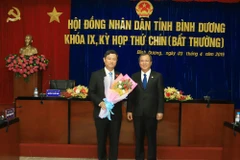Ông Trần Văn Nam (bên phải), Bí thư Tỉnh ủy tặng hoa chúc mừng ông Võ Văn Minh. (Nguồn: baobinhduong.vn)