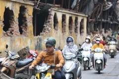 Người dân sinh sống tại đây phải đeo khẩu trang mỗi khi đi qua khu vực cháy nhà máy Bóng đèn Phích nước Rạng Đông. (Ảnh: Thành Đạt/TTXVN)