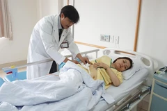 Bà Nguyễn Thị Như T được bác sĩ kiểm tra tình hình sức khỏe trước khi xuất viện. (Ảnh: Lê Xuân/TTXVN)