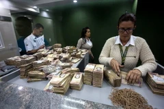 Nhân viên ngân hàng kiểm đồng 100 Bolivar tại Caracas. (Nguồn: EPA/TTXVN)