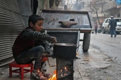 Một em bé Syria nấu ăn trên đường phố Aleppo. (Nguồn: AFP/TTXVN)