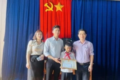 Ủy ban Nhân dân xã Kim Tân tặng Giấy khen cho em Kpă Nguyên vì đã có hành động dũng cảm cứu người bị đuối nước. (Ảnh: Quang Thái/TTXVN)