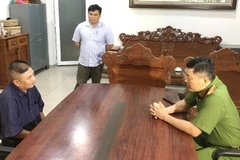 Trưởng Phòng Cảnh sát hình sự Võ Nhật Hồng Phúc đấu tranh với đối tượng Hứa Nghiệp Thắng-ngồi, bên trái. (Ảnh: TTXVN phát)