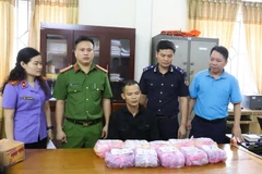 Đối tượng Nguyễn Thành Luân (giữa) và tang vật bị thu giữ. (Ảnh: TTXVN phát)