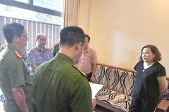 Cơ quan Công an đọc lệnh bắt bị can để tạm giam và lệnh khám xét chỗ đối với đối tượng Nguyễn Thị Nhung. (Ảnh: TTXVN phát)