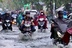 Người dân vượt dòng nước ngập trên đường Tô Ngọc Vân, thành phố Thủ Đức, Thành phố Hồ Chí Minh. (Ảnh: Hồng Giang/TTXVN)