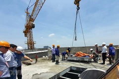 Lực lượng cưỡng chế cắt sàn mái tầng 18 công trình 8B Lê Trực, Hà Nội. (Ảnh: Mạnh Khánh/TTXVN)