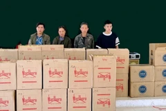 Bốn đối tượng vận chuyển trái phép thuốc lá cùng tang vật tại Đồn Biên phòng Tổng Cọt. (Ảnh: TTXVN phát)
