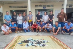 Các đối tượng tham gia đá gà qua mạng cùng tang vật tại cơ quan Công an. (Ảnh: TTXVN phát)