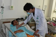 Bác sỹ thăm khám cho bệnh nhân H.V.Q. (Ảnh: Hoàng Nhị/TTXVN)