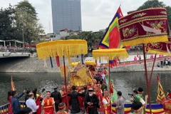 Phục dựng nghi thức "Độ hà," được thực hiện bằng việc trai đinh khiêng kiệu lội qua sông Tô Lịch mà không đi trên cầu, hàm ý “con không đi trên đầu cha,” tại lễ hội Chùa Láng. (Ảnh: TTXVN phát)
