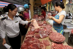 Nhân viên thú y kiểm tra hộ kinh doanh thịt lợn tại chợ. (Ảnh: Vũ Sinh/TTXVN)