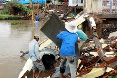 Người dân khắc phục hậu quả vụ sạt lở đê sông ở ấp Thạnh Đức. (Ảnh: Trung Hiếu/TTXVN)