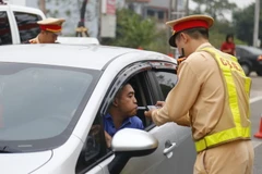 Cảnh sát giao thông kiểm tra nồng độ cồn của lái xe. (Ảnh: Nam Sương/TTXVN)