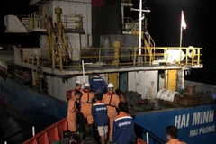 Sau khi được Tàu SAR27-01 cứu nạn do rơi xuống biển, ba thuyền viên (áo xanh đen) về lại tàu Hải Minh 36. (Ảnh: TTXVN phát)