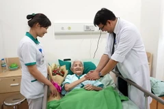 Nhân viên y tế thăm hỏi tặng hoa chúc mừng cụ bà đã khỏe lại chuẩn bị xuất viện. (Ảnh: Kiều Oanh/Vietnam+)