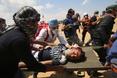 Chuyển người biểu tình Palestine bị thương sau các cuộc đụng độ với binh sỹ Israel tại khu vực biên giới Dải Gaza với Israel ngày 14/5. (Nguồn: AFP/TTXVN)
