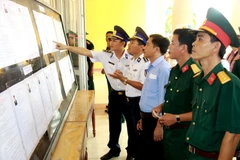 Cử tri thuộc các đơn vị lực lượng vũ trang huyện đảo Lý Sơn, Quảng Ngãi, tìm hiểu tiểu sử các ứng cử viên trước khi tiến hành bỏ phiếu. (Ảnh: Vĩnh Trọng/TTXVN)