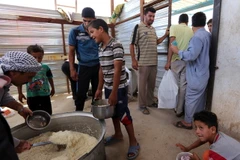 Trẻ em Iraq xếp hàng nhận lương thực cứu trợ tại khu vực Dora, ngoại ô thủ đô Baghdad ngày 31/5, sau khi phải rời bỏ nhà cửa ở khu vực chiến sự. (Nguồn: AFP/TTXVN)