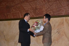 Đại diện ĐSQ Việt Nam tại Pháp (trái) trao tặng hoa cho anh Phạm Thành Trung, Chủ tịch Quỹ "Đồng hành." (Ảnh: Bích Hà/Vietnam+)