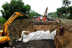 Một nửa mặt đường Quốc lộ 1 bị sạt lở nghiêm trọng đang được các đơn vị khẩn trương thi công. (Ảnh: Thế Lập/TTXVN)