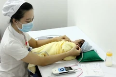Nhân viên y tế sàng lọc khiếm thính cho sơ sinh tại Trung tâm Sàng lọc – chẩn đoán trước sinh và sơ sinh. (Ảnh: Dương Ngọc/TTXVN)