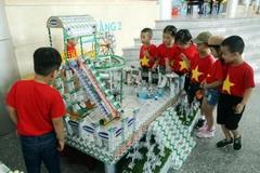 Phụ huynh học sinh và các em nhỏ thích thú xem các đồ dùng, đồ chơi, mô hình từ vỏ hộp sữa đã qua sử dụng tại Ngày hội SHĐ Đà Nẵng.