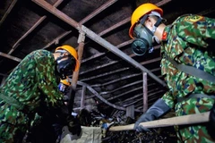 Lực lượng Binh chủng Hoá học thu gom chất thải, giải phóng hiện trường để tiến hành tẩy độc mặt nền nhà xưởng. (Ảnh: Dương Giang/TTXVN)