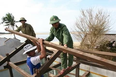 Bộ đội Biên phòng tỉnh Quảng Nam giúp đỡ nhân dân sửa chữa nhà cửa do hậu quả của cơn bão số 9 gây ra. (Ảnh: Huy Hùng/TTXVN)