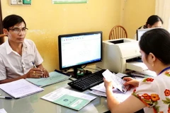 Nhân viên Bảo hiểm Xã hội huyện Phù Cừ thực hiện giao dịch thẻ bảo hiểm y tế với các đại lý xã, phường. (Ảnh: Dương Ngọc/TTXVN) 