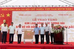 Lãnh đạo tỉnh Lào Cai và Tập đoàn Công nghiệp Than-Khoáng sản Việt Nam (bên phải) trao tấm đồng tượng trưng cho lãnh đạo tỉnh Sơn La (bên trái). (Ảnh: Quốc Khánh/TTXVN)