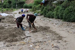 Nhân dân khắc phục đoạn đường bị sạt lở tại xã Pa Vây Sử. (Ảnh: Quý Trung/TTXVN)