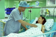Phó giáo sư-tiến sỹ, bác sỹ Nguyễn Hoàng Định thăm khám cho bệnh nhân sau khi phẫu thuật thay van tim bằng kỹ thuật Ozaki. (Ảnh: Phương Vy/TTXVN)
