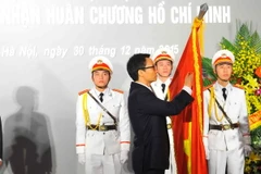 Phó Thủ tướng Vũ Đức Đam gắn Huân chương Hồ Chí Minh lên lá cờ truyền thống của Trường Đại học Mỹ thuật Việt Nam. (Ảnh: Minh Đức/TTXVN)