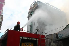 Lực lượng Cảnh sát phòng cháy chữa cháy đang nỗ lực dập lửa ngăn cháy lan sang quán karaoke, khách sạn liền kề. (Ảnh: Sỹ Tuyên/TTXVN)