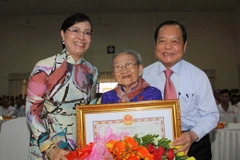 Bí thư Thành ủy TP. Hồ Chí Minh Lê Thanh Hải trao tặng danh hiệu "Bà mẹ Việt Nam Anh hùng” cho Mẹ Dương Thị Tình tại buổi lễ. (Ảnh: Thanh Vũ/TTXVN)