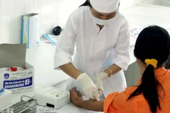Cán bộ y tế của Trung tâm phòng chống HIV/AIDS tỉnh Ninh Bình lấy mẫu máu xét nghiệm HIV/AIDS cho khách hàng. (Ảnh: Dương Ngọc/TTXVN)