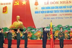 Chủ tịch nước Trương Tấn Sang gắn Huân chương Quân công hạng Nhất lên lá cờ truyền thống của Tổng cục Hậu cần. (Ảnh: Trọng Đức/TTXVN) 