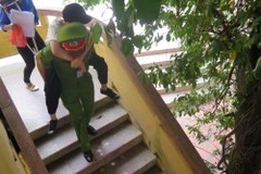 Sinh viên tình nguyện Học viện Cảnh sát Phan Tuấn Hùng cõng thí sinh Nguyễn Thị Ánh Dương ra khỏi phòng thi sau khi kết thúc môn thi Ngữ văn, sáng 2/7. (Ảnh: Mạnh Minh/TTXVN)