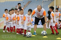 HLV Park Hang-seo hướng dẫn các em học sinh khởi động trước khi chơi bóng đá. (Ảnh: Trung Kiên/TTXVN)