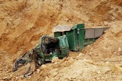 Tại hiện trường, chiếc xe tải bị vùi lấp trong đống đất đá. (Ảnh: TTXVN phát)